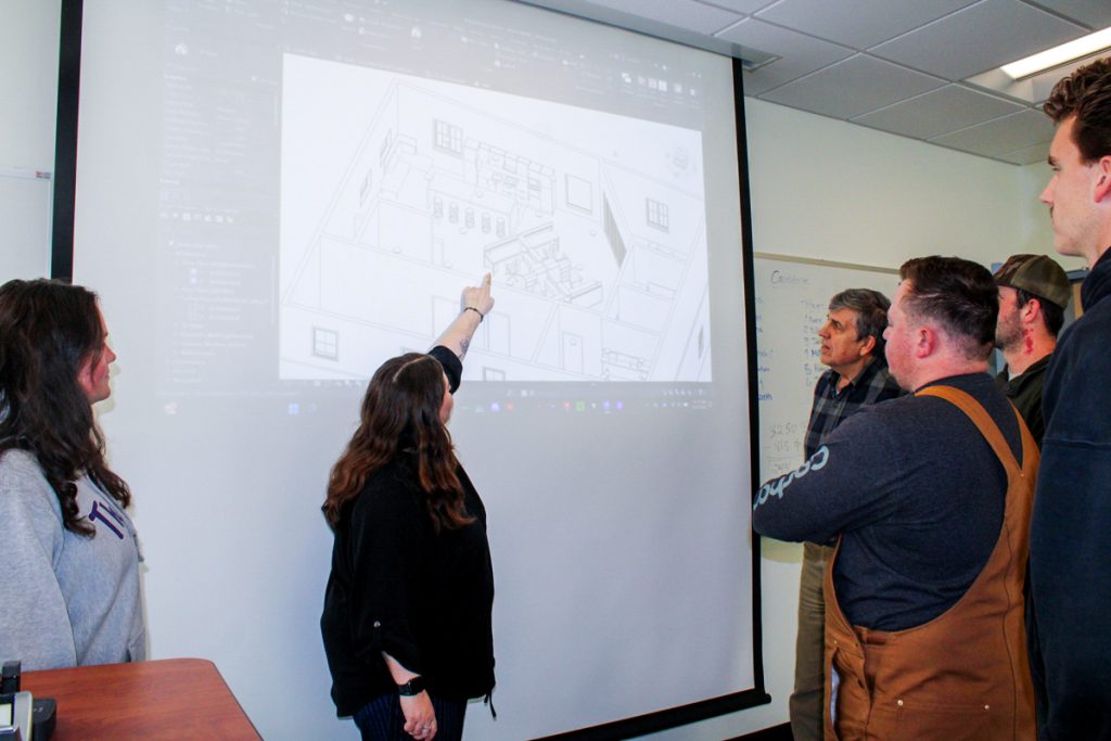 A team of WCU construction management students point out features in their proposed building design and renderings for AWAKE to faculty member Dr. Chris Cox
