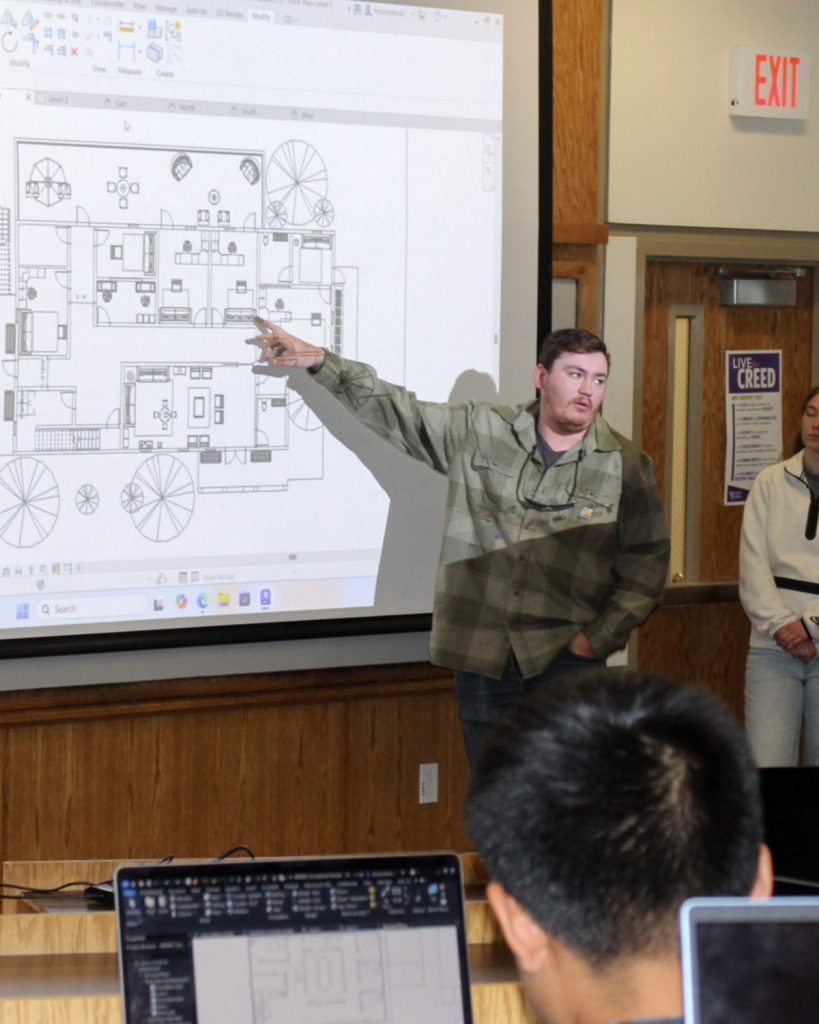 A WCU construction management student points out a feature of a building design prepared for AWAKE Children's Advocacy Center.