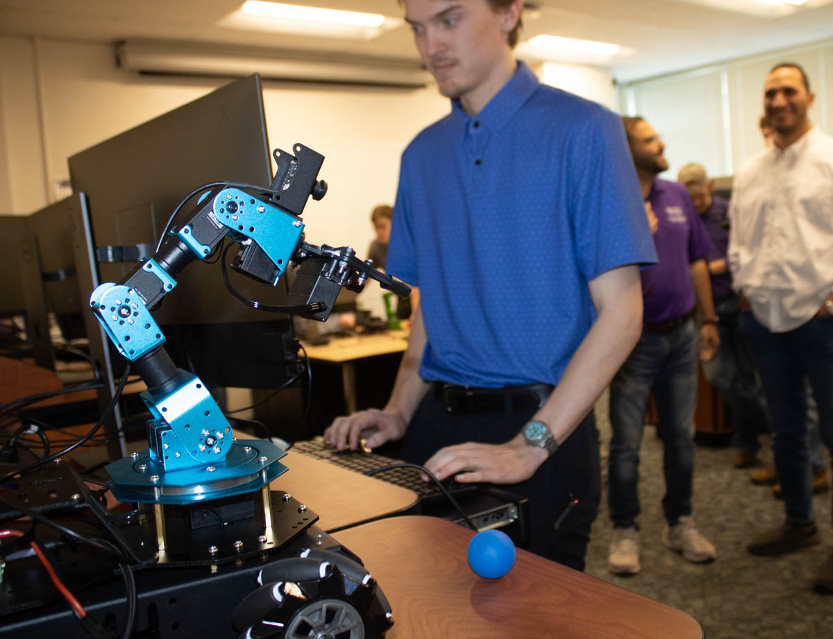 A student types on a computer to update code related to the Optimus robot