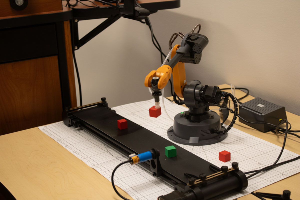 Orange Medusa robots pick up red block from a conveyor belt