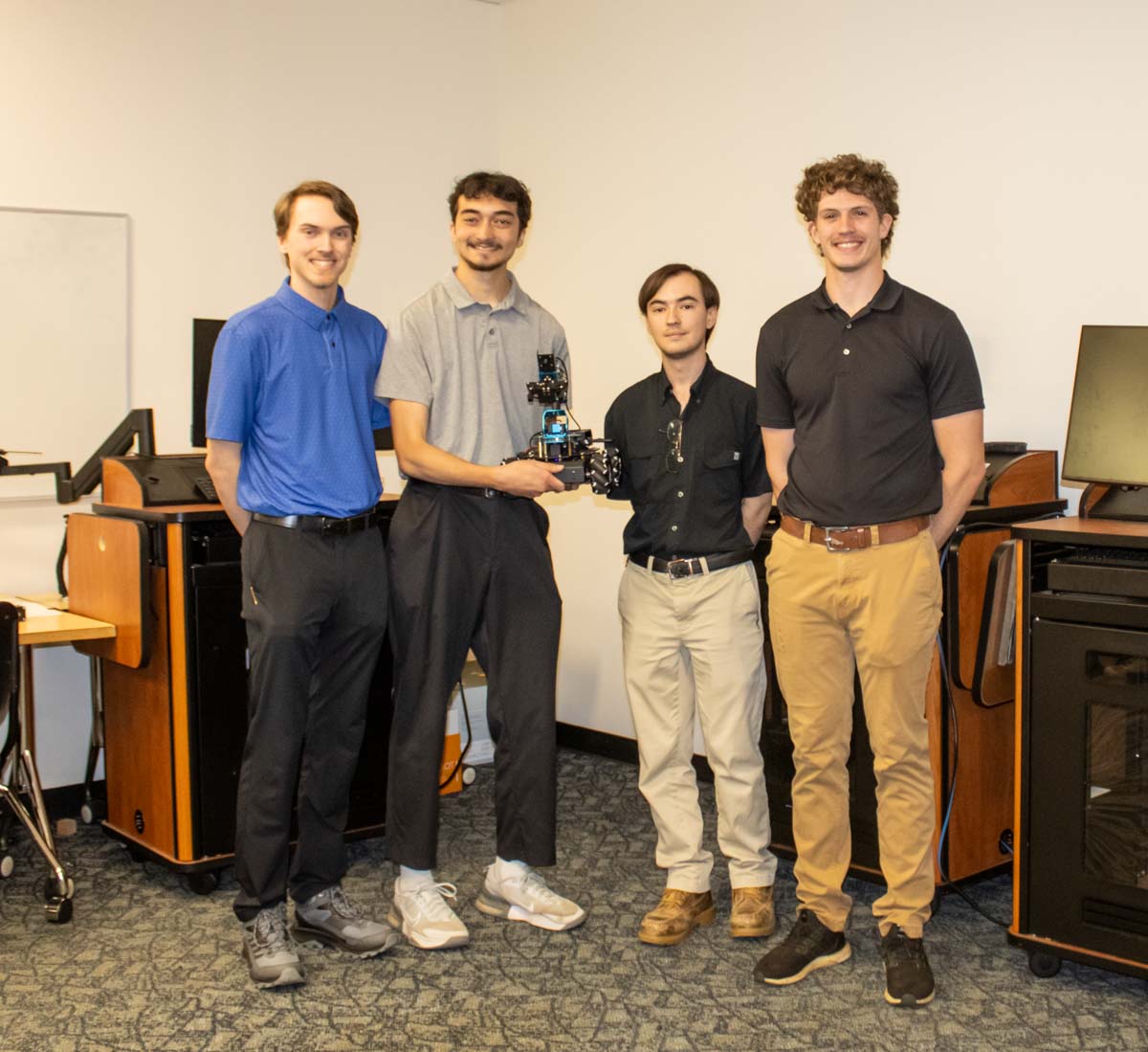 Four students with the Optimus team stand and hold the blue Optimus robot