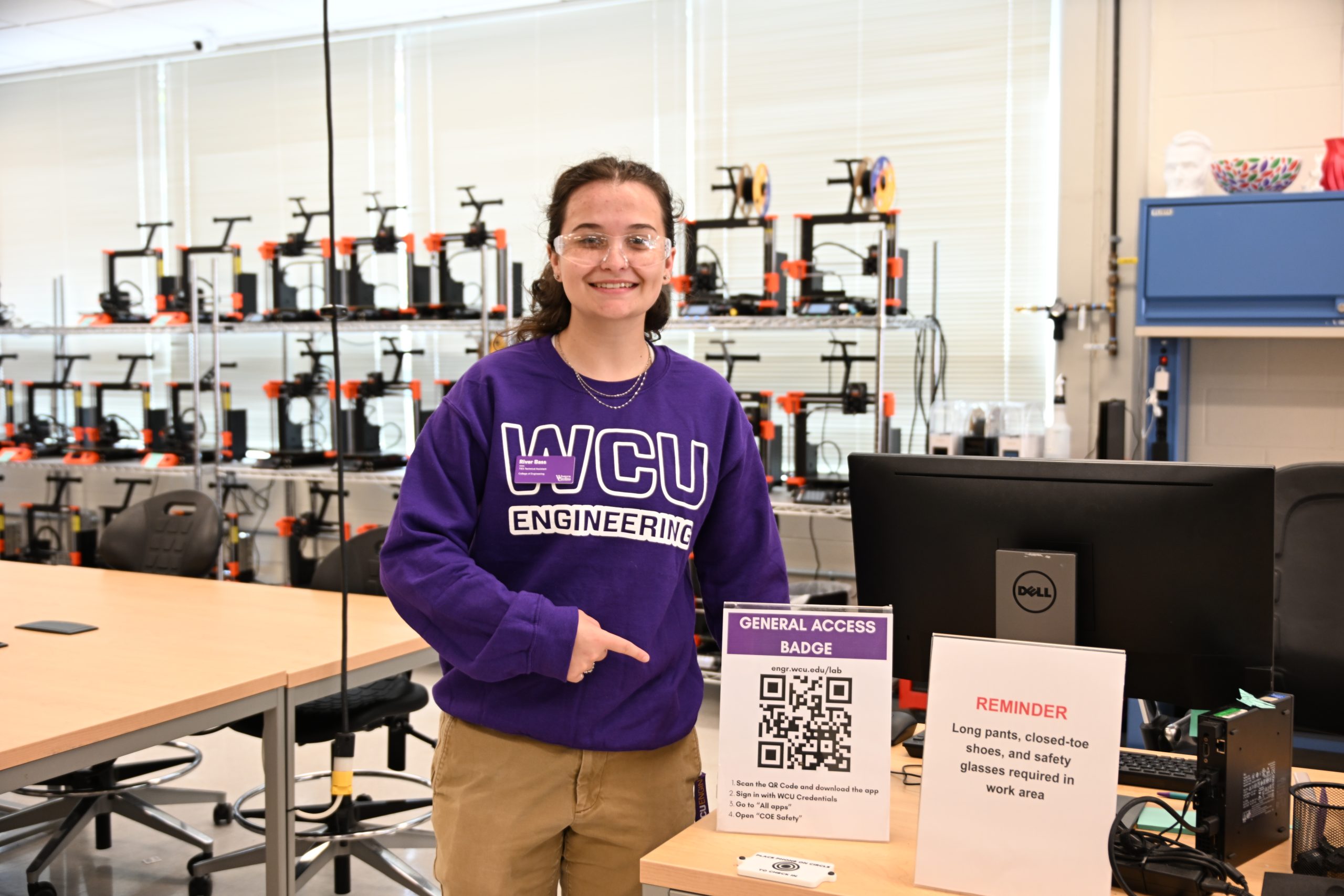 A woman stands beside the new safety badge system QR code