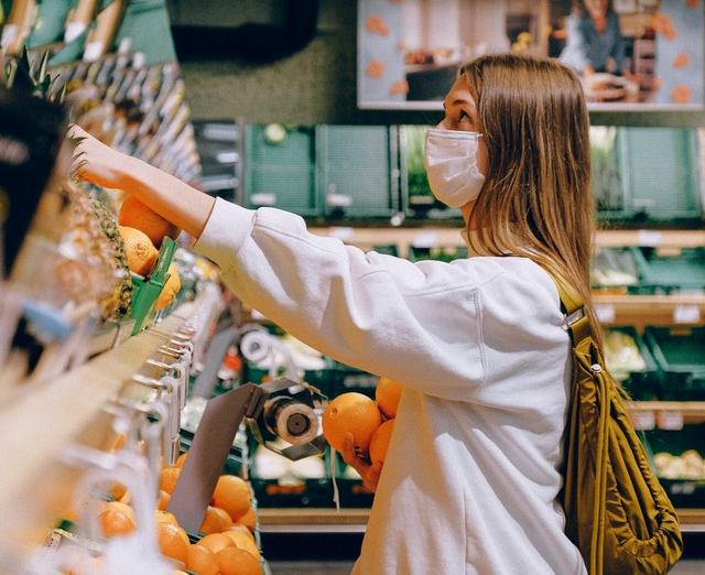 Woman shops in grocery story wearing face mask.