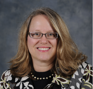 Professional studio portrait of a middle-aged Asian woman wearing a cream cable-knit sweater against a gray background.