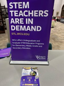 Purple sign that reads "STEM TEACHERS ARE IN DEMAND STL.WCU.EDU WCU offers Undergraduate and Graduate STEM Education Programs for Elementary, Middle Grades and Secondary Education."