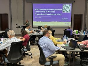 Educators listening to Dr Bricker present. Board reads "WNC Elementary STEM/Science Community of Practice Professional Development Day"